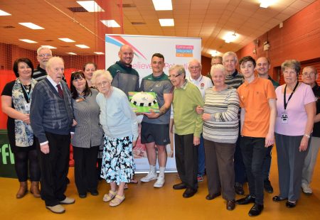 Vikings Players Jack Buchanan and Eamon O'Carroll present anniversary cake to members of The Chemics Cafe