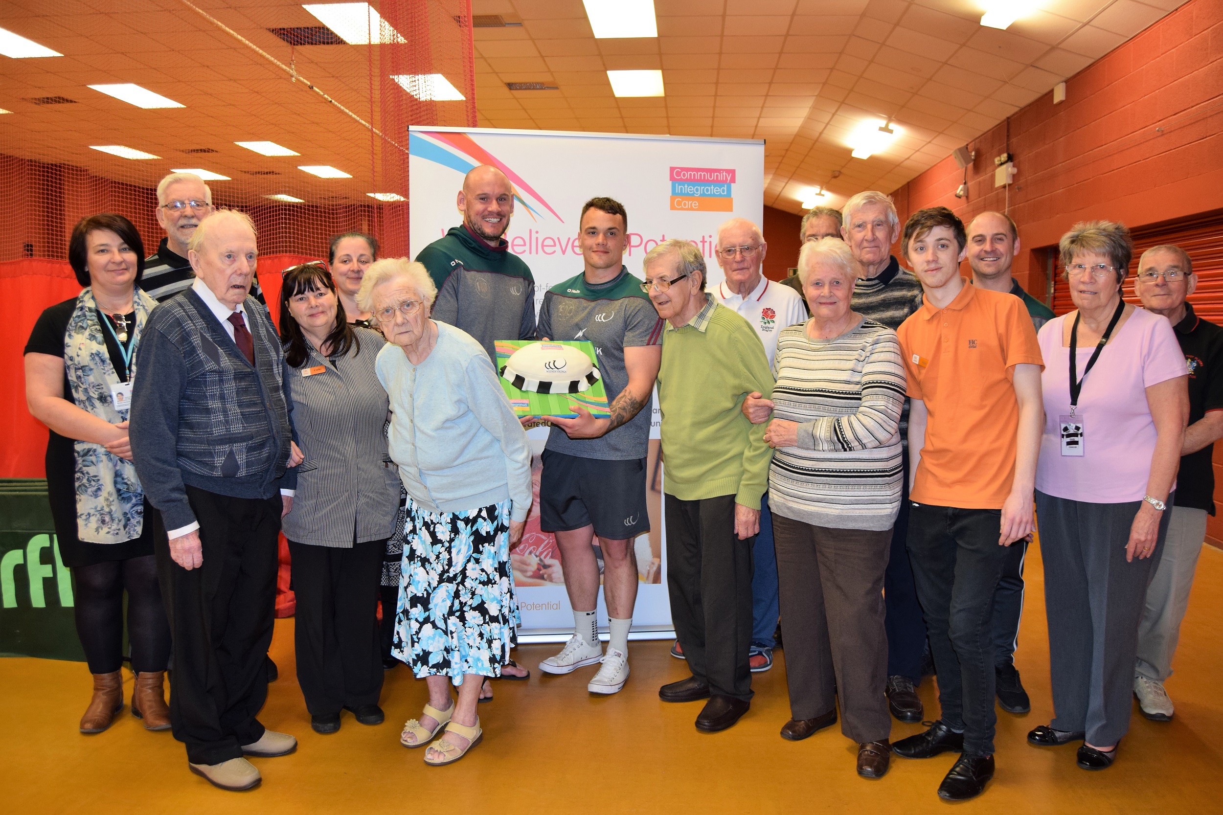 Vikings Players Jack Buchanan and Eamon O'Carroll present anniversary cake to members of The Chemics Cafe