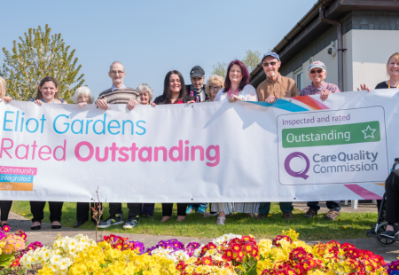 Eliot Gardens colleagues and people we support holding Outstanding banner for one of the UK's largest health and social care charities