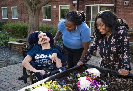 Three people standing by flower bed