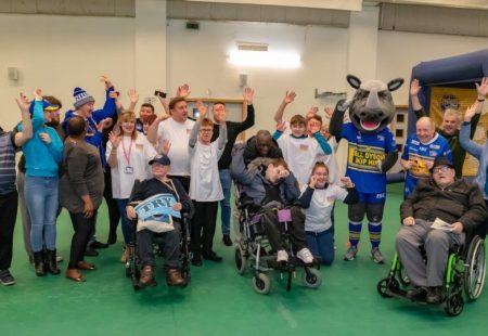 Group of people cheering at the launch of the Leeds Rhinos and Community Integrated Care Partnership