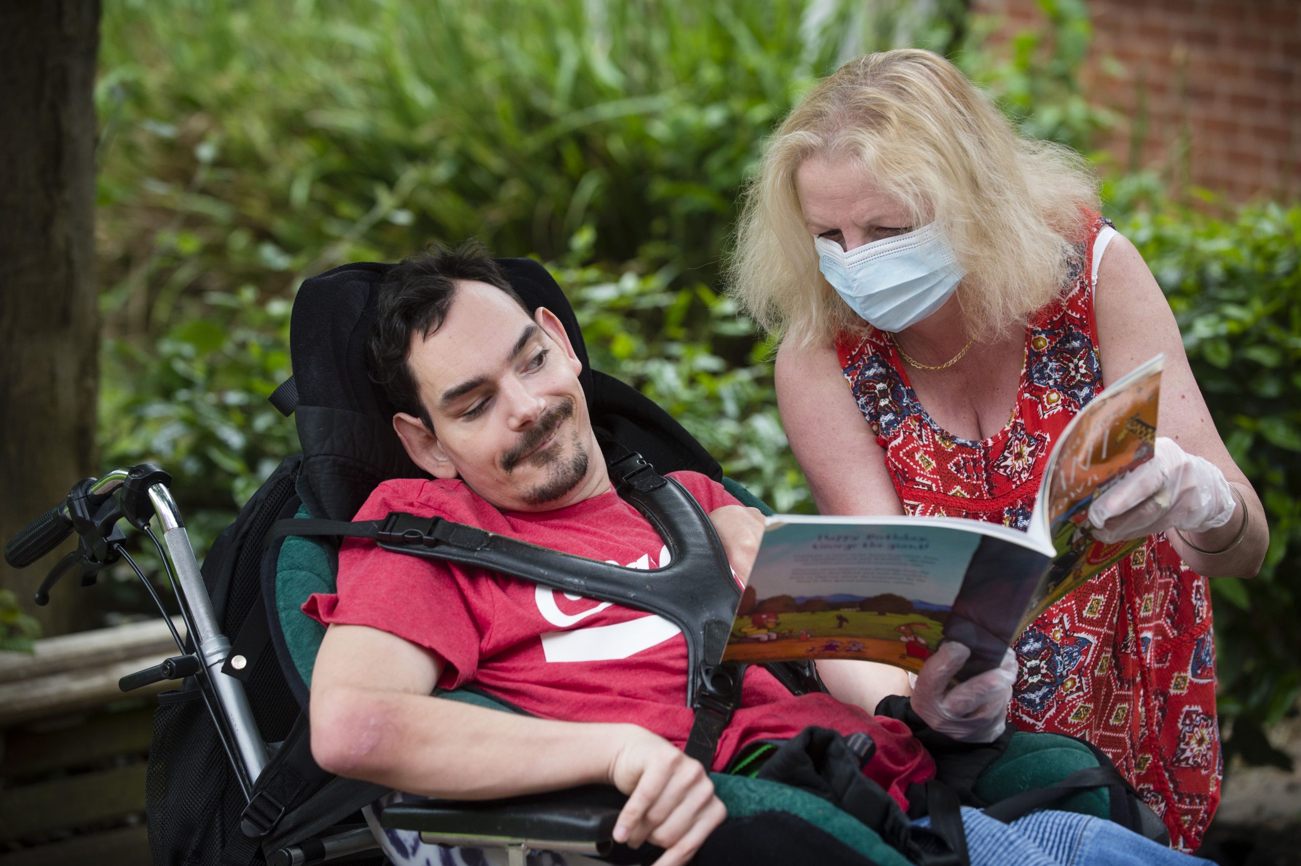 Person supported in wheelchair reading book