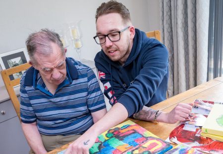 Person supported with colleague doing arts and crafts