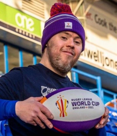Oliver Thomason holding a rugby league World Cup 2021 ball in stadium
