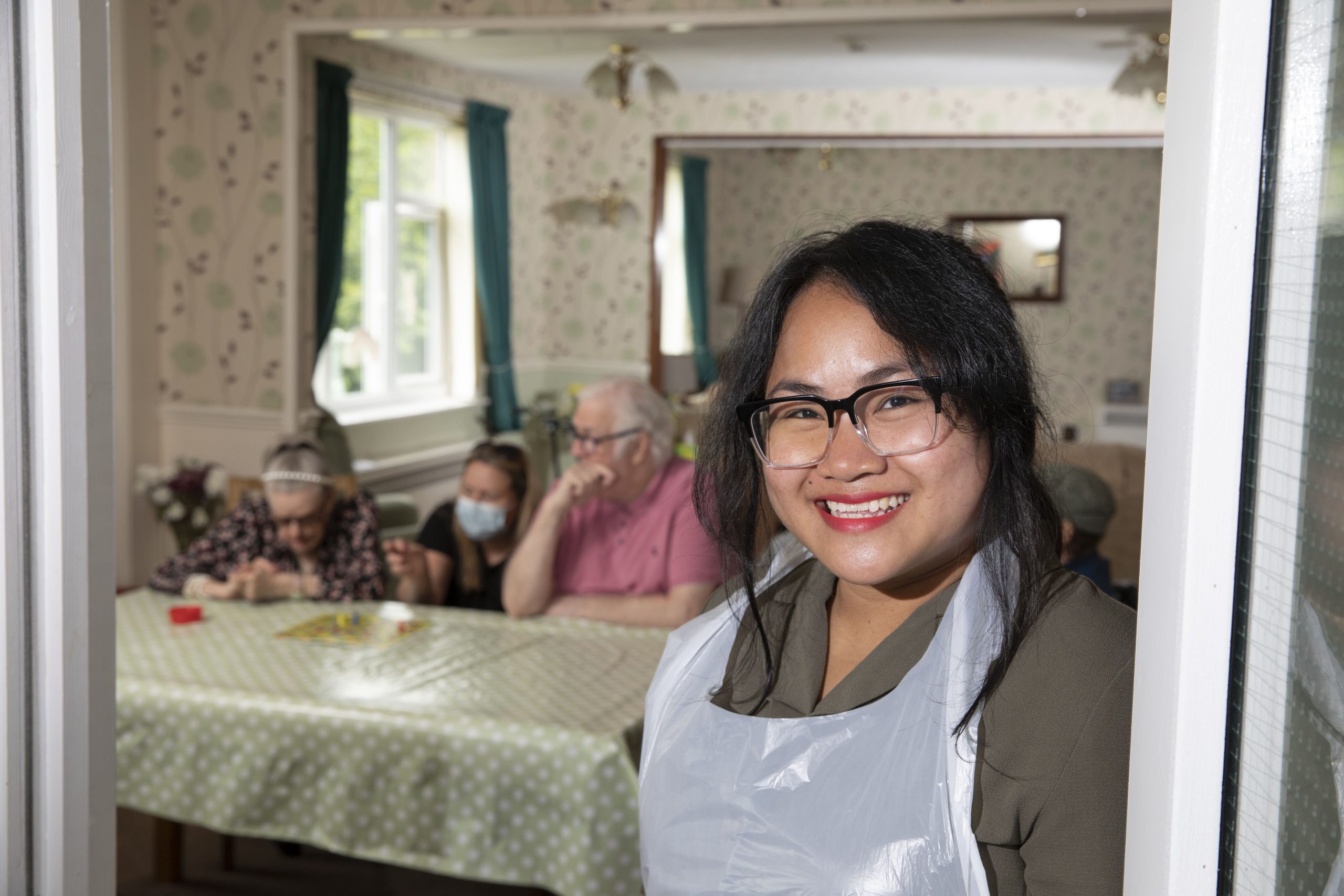 Woman in apron with group behind at table