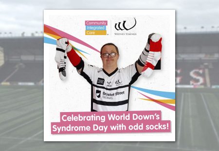 Person supported holding off socks for world Down syndrome day