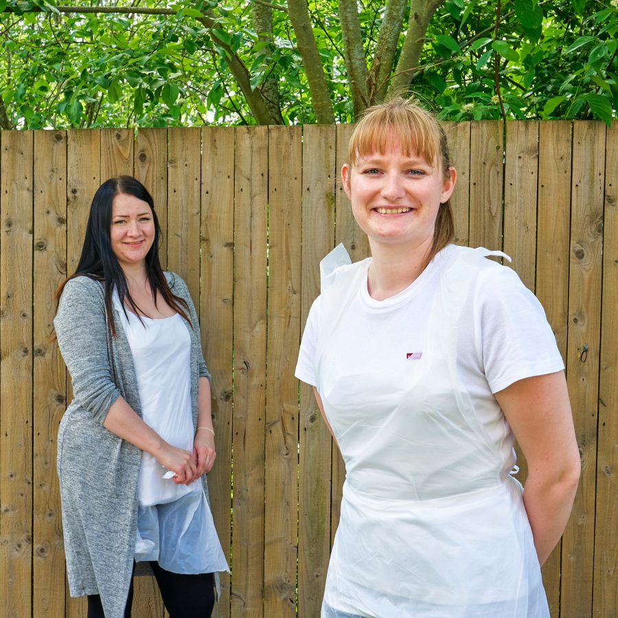 Two women in front of fence