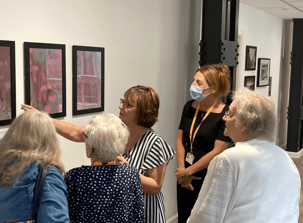 Photography Club participant, Marie, explains a selection of her photography to a crowd of guests.