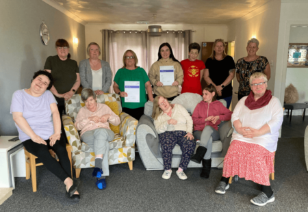 Colleagues and people supported at Mill Road and Lismore servcies in Armadale sit together, holding their 'Good' inspection reports.