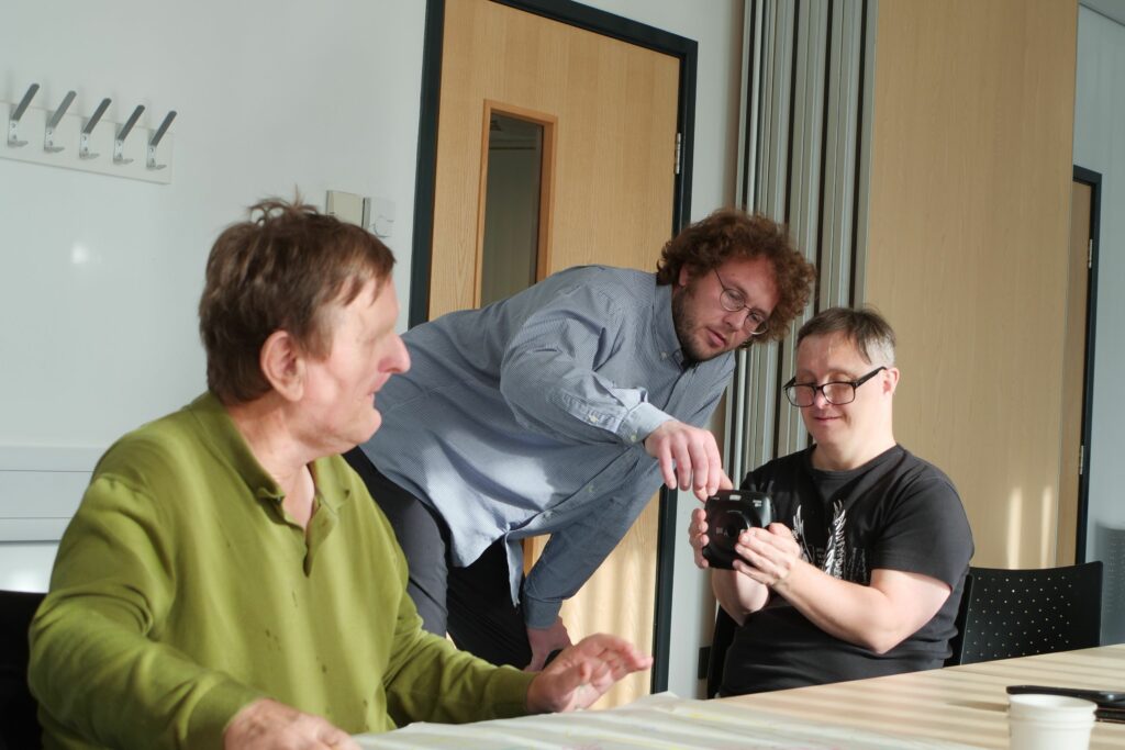 Sam Batley teaching people we support how to use a camera.