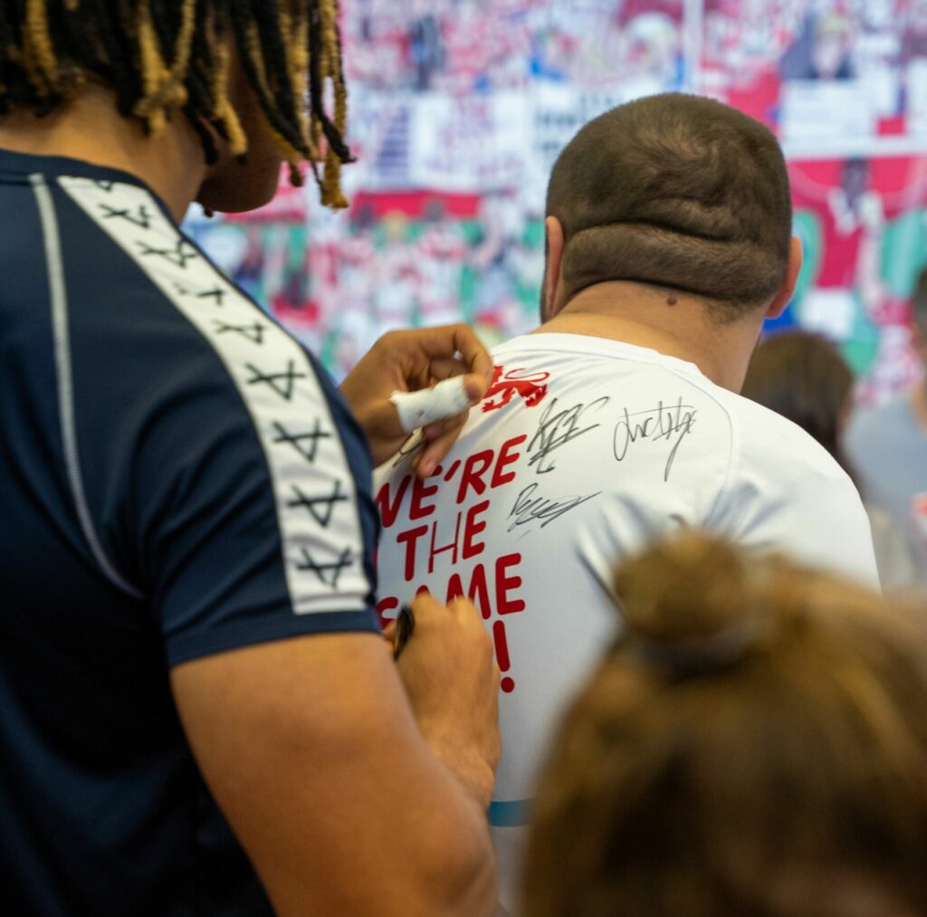 England RLWC 21 player signs the shirt for an Inclusive Volunteer.