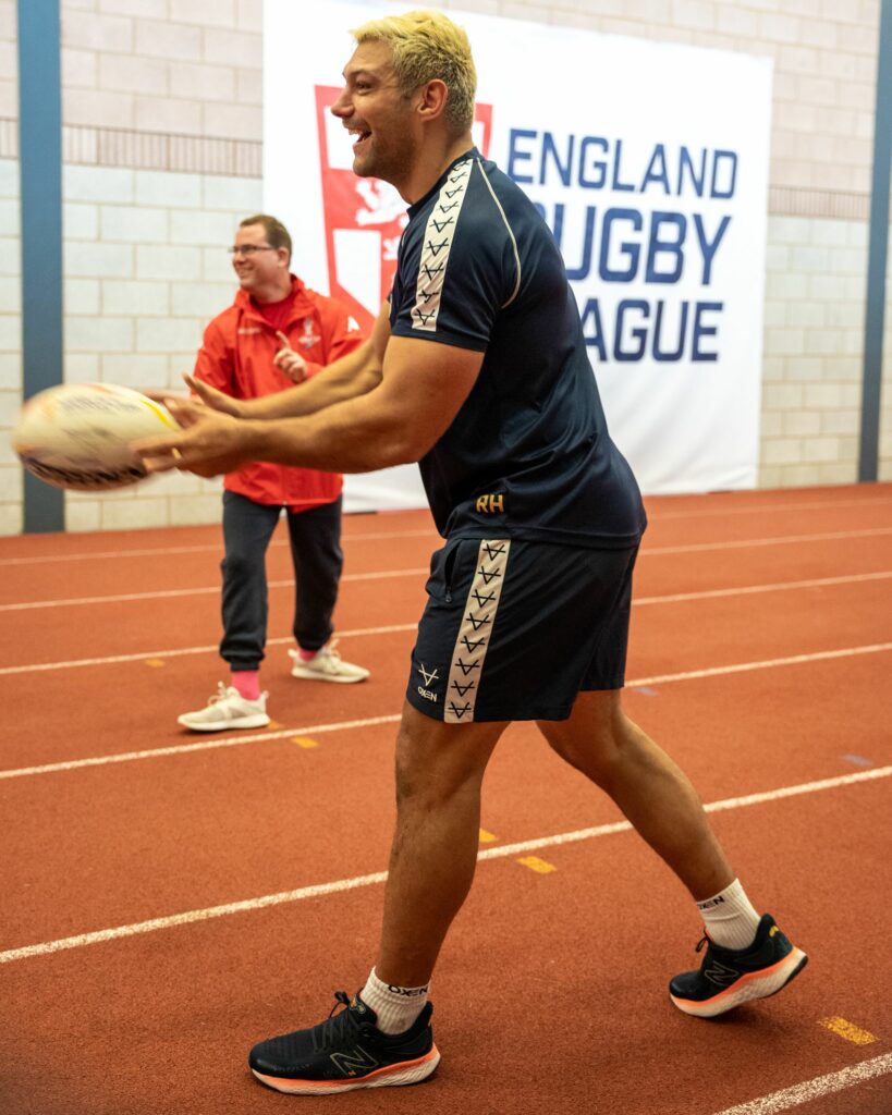 England RLWC player trhows rugby ball to inclusive volunteer