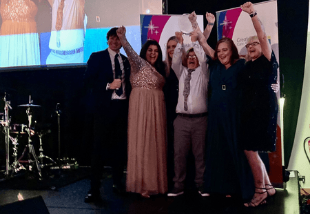 The team from kirkdale House cheering as they collect their award.