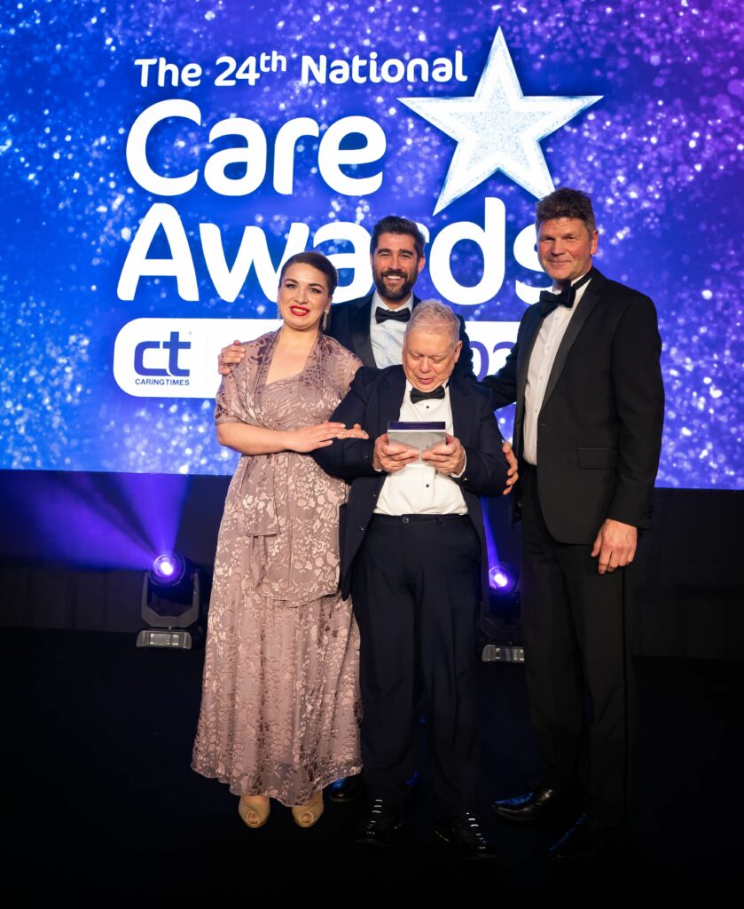 Aaron adn Rebeca collect the National Care Award on stage, for What To Do