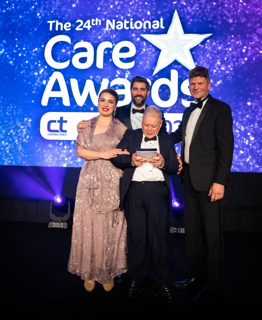 Aaron adn Rebeca collect the National Care Award on stage, for What To Do