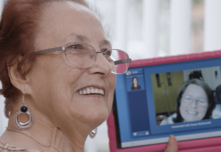 Woman smiling, screen in the background showing technology enabled care in practice