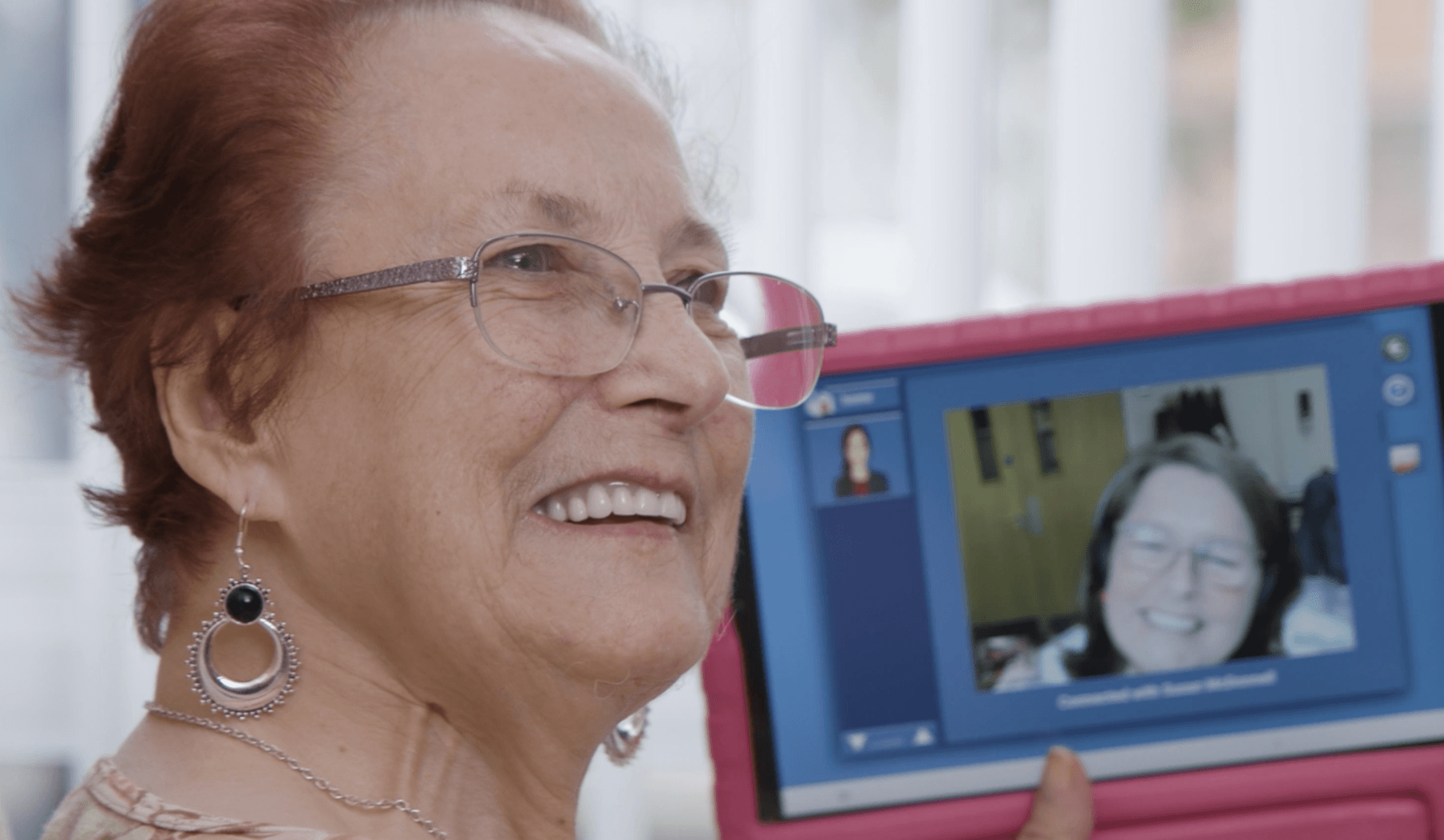 Woman smiling, screen in the background showing technology enabled care in practice