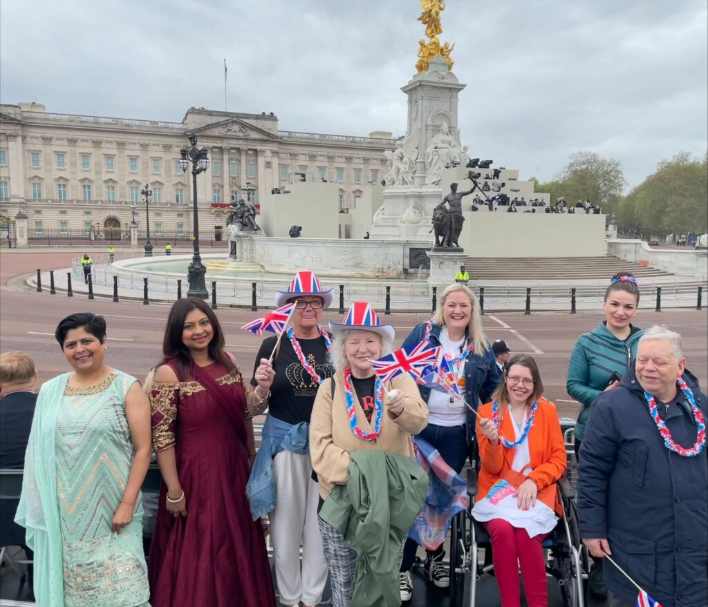 Colleagues and people supported by Community Integrated Care stood outside Buckingham Palace holding Union Jack flags, to celebrate the King's Coronation.