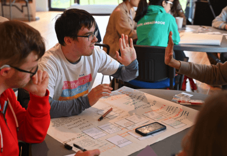 Volunteer, Jake, high fives a teammate at Young Voices workshop.