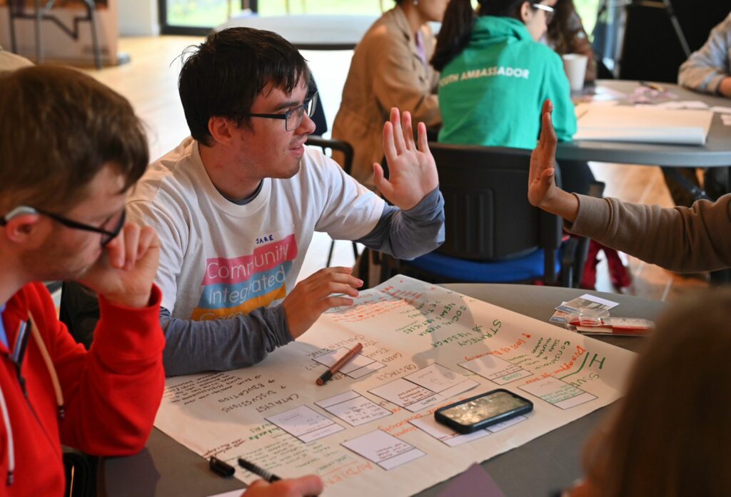 Volunteer, Jake, high fives a teammate at Young Voices workshop.
