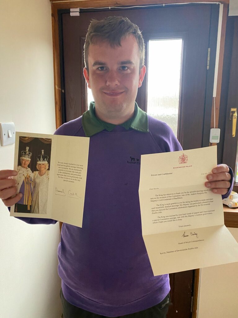 Kevin, a person supported by Community Integrated Care, holds a letter from the King's Royal Correspondent and a card signed by the King, with a picture of the King and Queen Consort.