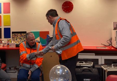 Barry shakes hands with his colleague, accepting his card and gift.