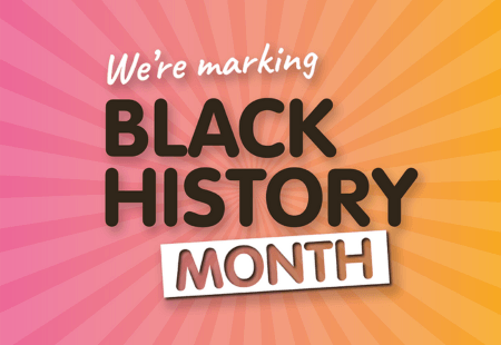 Pink and orange sign reads 'We're Marking Black History Month'.