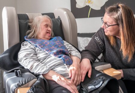 Support worker and person we support sitting in a chair, looking at eachother.