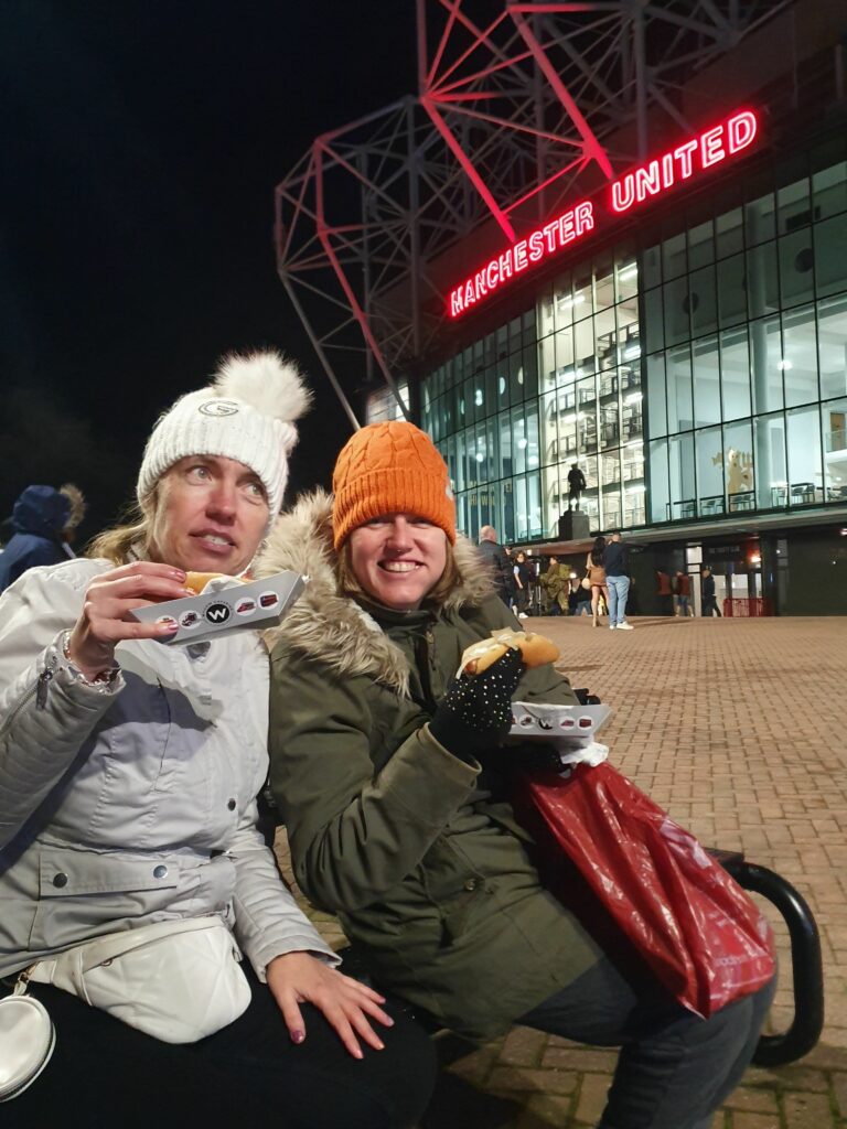 Two people we support stood outside Old Trafford Stadium eating hotdogs, ahead of the Super League Grand Final.