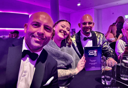 Threee Community Integrated Care colleagues smiling to camera, holding the National Care Awards trophy.