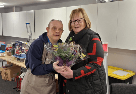 A person we support hands flowers to Linda Gray, Inspire CEO, and wishes her fond farewell.
