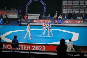A taekwondo match taking place on a blue floor.