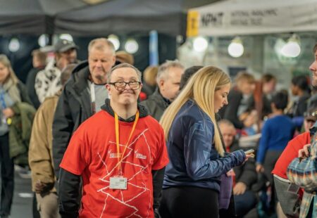 Inclusive volunteer in official red event t-shirt wearing a lanyard at the event