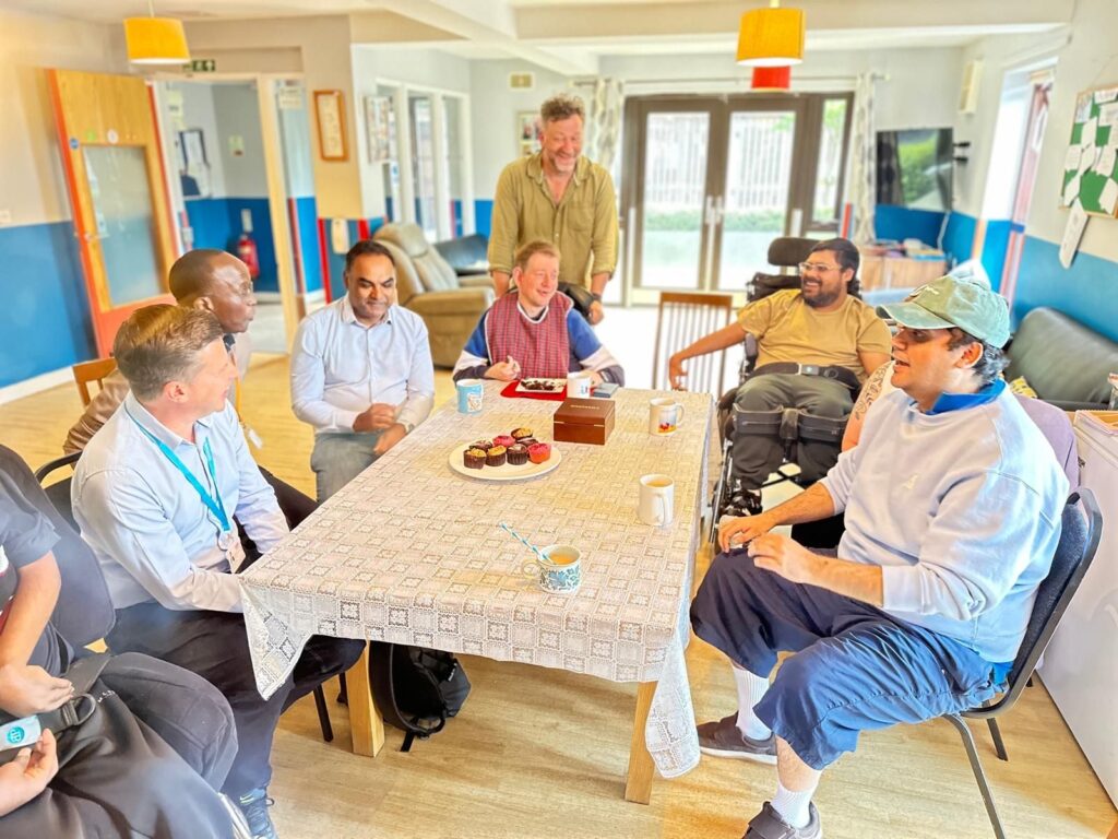 Trustee Dinesh enjoys tea and cakes with colleageus and people supported at Millers Yard.