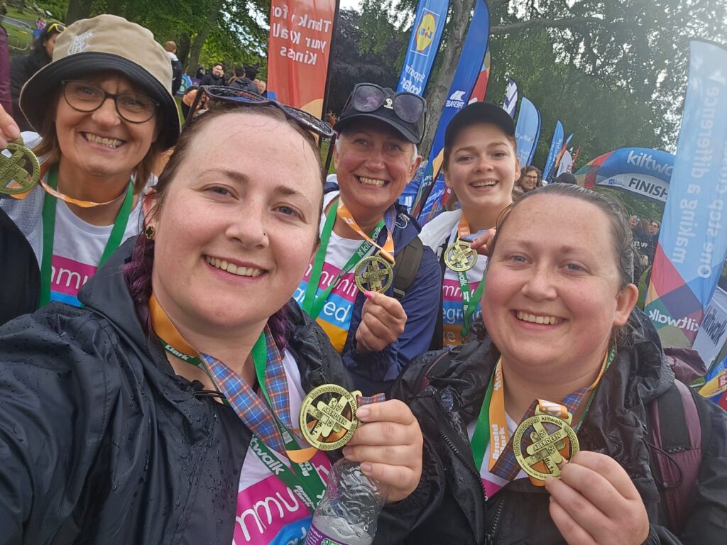 Colleagues holding their medals from the Aberdeen Kiltwalk.