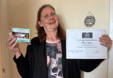 Mhairi holding up her 20 years at Rainbows certificate