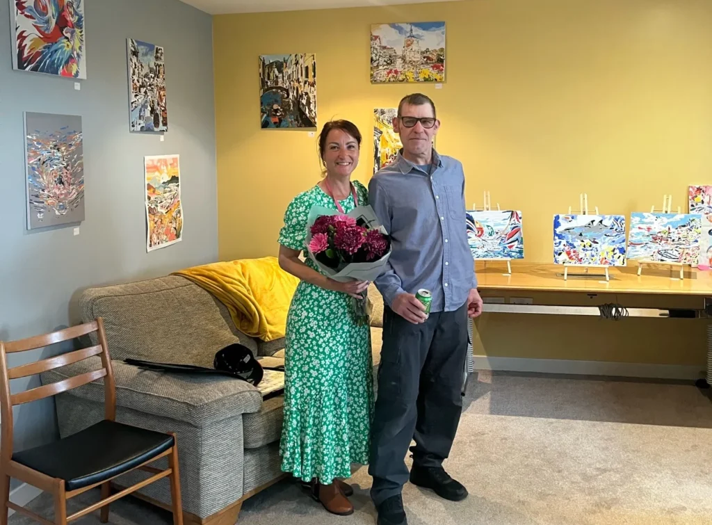 Pete standing next to this artwork with his support worker, sasha