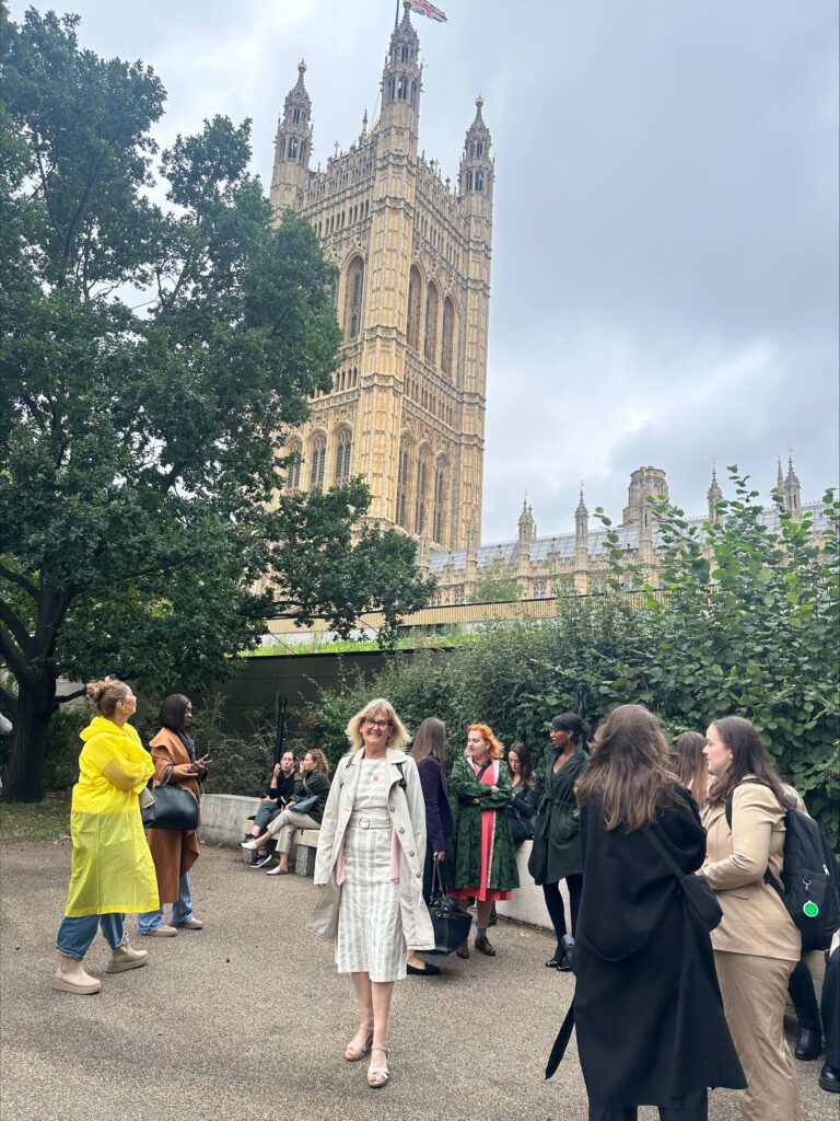 Support Worker, Amandajayne Swan, stands in front of the House of lords, smiling to camera.