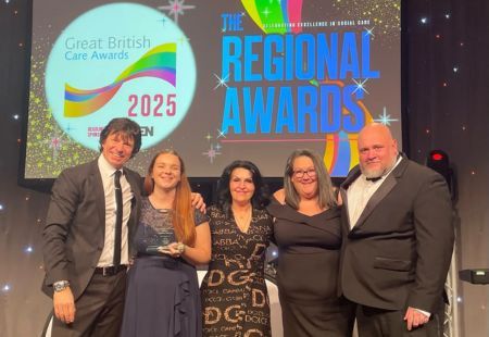 Four representatives from the team at Brickfields stand on stage collecting their award. They are all dressed in black tie attire, smiling to camera.