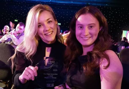 Sophie and Caitlin from our Partnerships team are smiling to camera holding their award trophy.