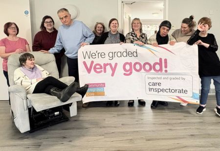 The team and people supported at Colleonard Court care home in Banff smile to camera, holding a banner that celebrates them having achieved Very Good in all areas, in their latest inspection from the Care Inspectorate.