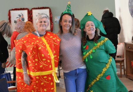 Service Leader, Carolyn Housbey dressed as a Christmas present,  Volunteer, Claire Ryder with a Christmas tree hat on, and Support Worker, Paula Tonim dressed as a Christmas tree.