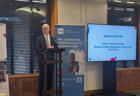Care Minister, Stephen Kinnock MP stands in front of a podium, addressing the audience at SCIE's report launch.