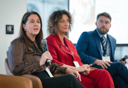 Community Integrated Care managing Director, Sam Brennan, sits on a sofa with two other care leaders, onstage at the LaingBuisson Care Summit North. Sam is speaking into a microphone.