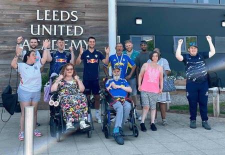 A group of people stood outside Leeds United with Ilia Gruev. They're all smiling and cheering to camera.