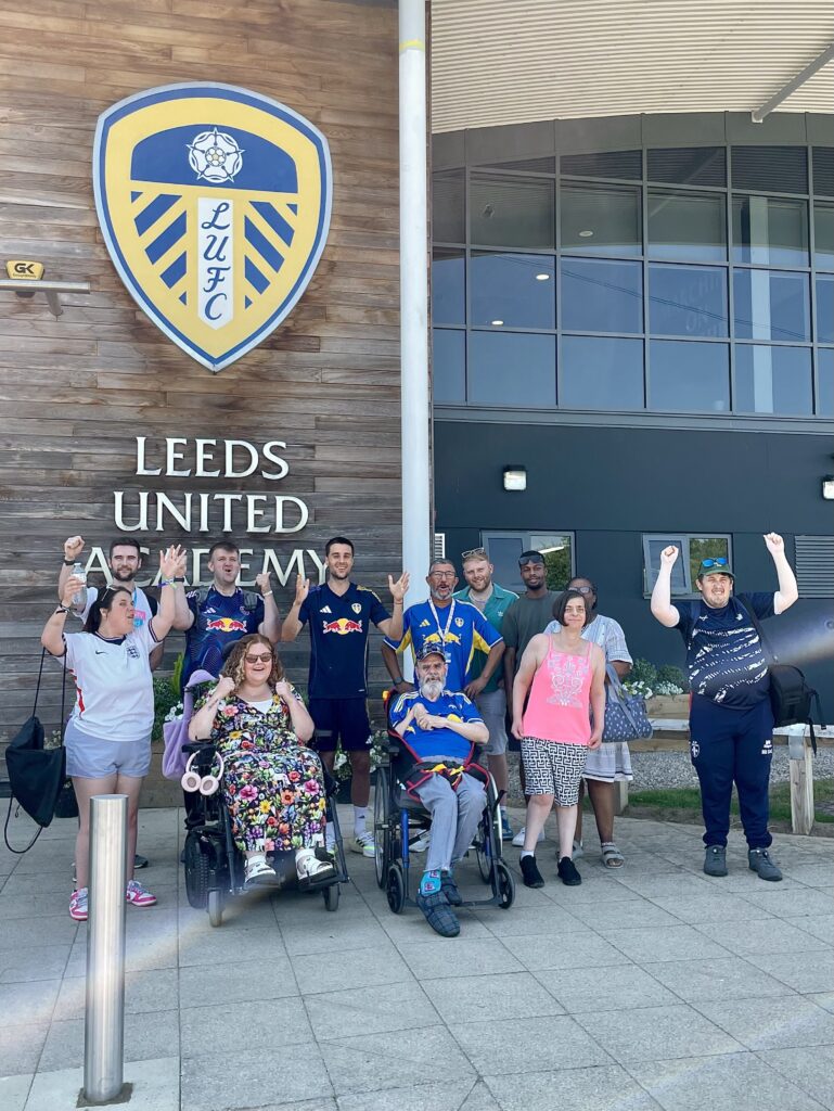 People supported by Community Integrated Care stand with Ilia, outside Leeds United.