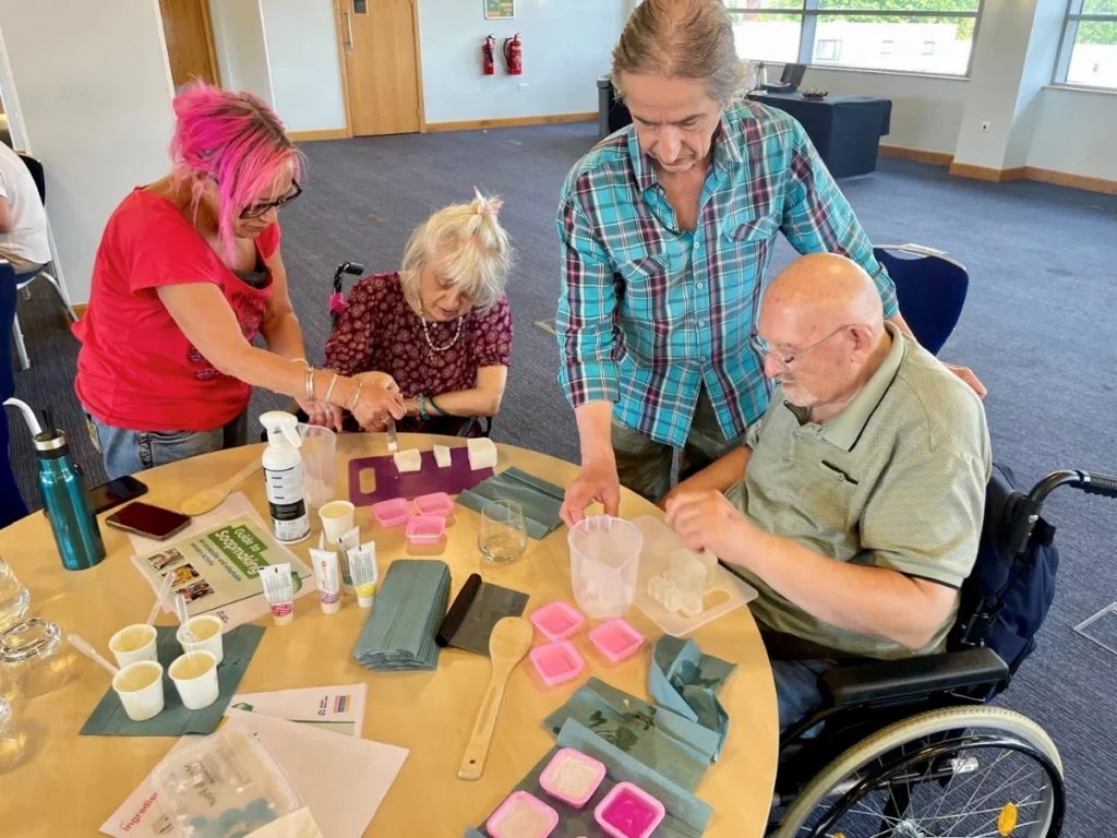 Four people sat around a table making soaps