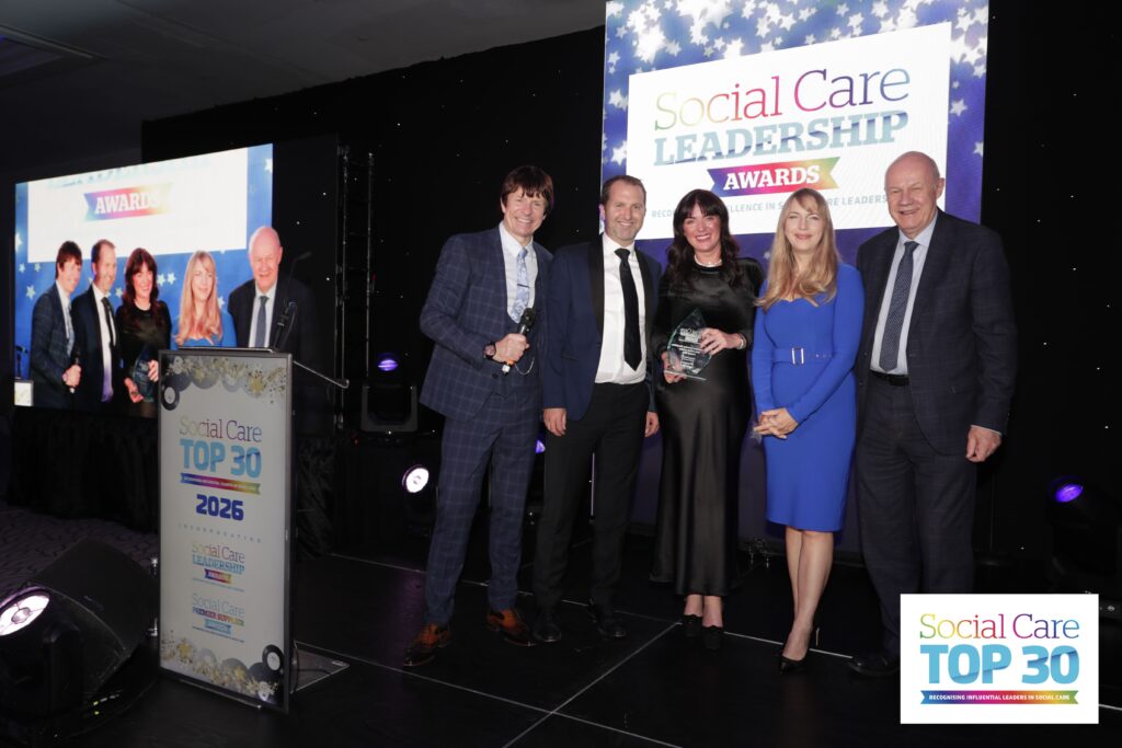 Sara murphy on stage with four awards representatives, collecting her award at the Social Care Leadership Awards.