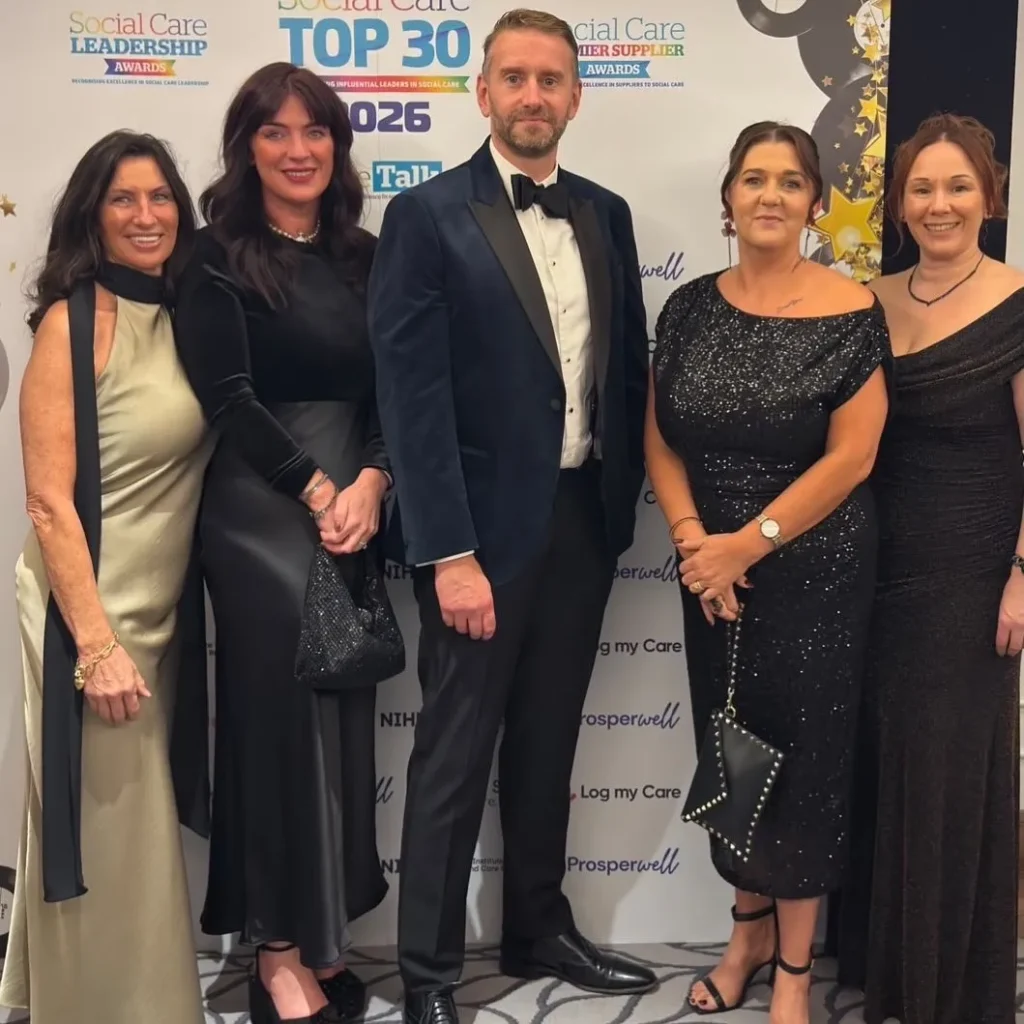 A group of Community Integrated Care leaders stand in front of an awards backdrop for the Social Care Leadership Awards.