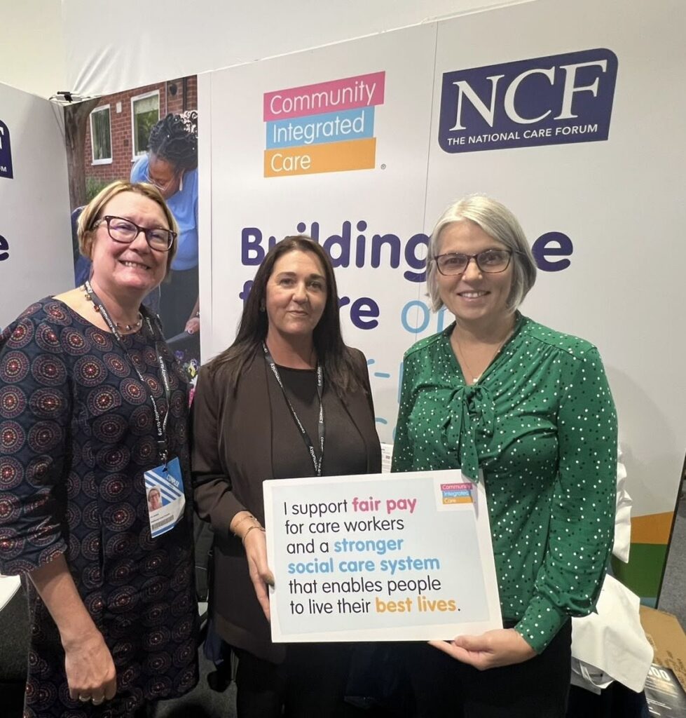 Three people stood in front of an exhibition stand which reads 'Building the Future of Not-for-profit social care'